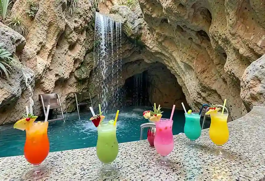 Natural stone rock grotto with a built-in spa waterfall and swim-up bar stools