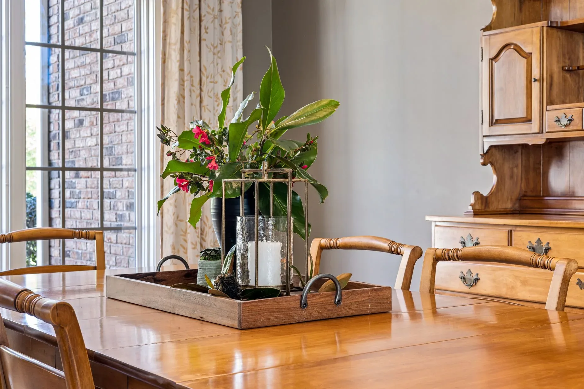 18 Cozy Kitchen Decor Ideas for a Warm Home A beautifully arranged flower centerpiece and candle on a wooden dining table in a classic interior setting.