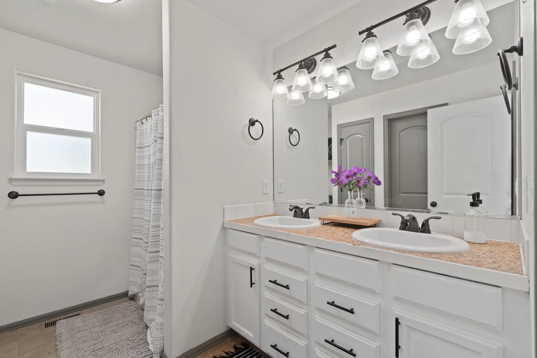15 White Bathroom Aesthetic Ideas on a Budget A chic bathroom features a double vanity, decorative lighting, and elegant fixtures.