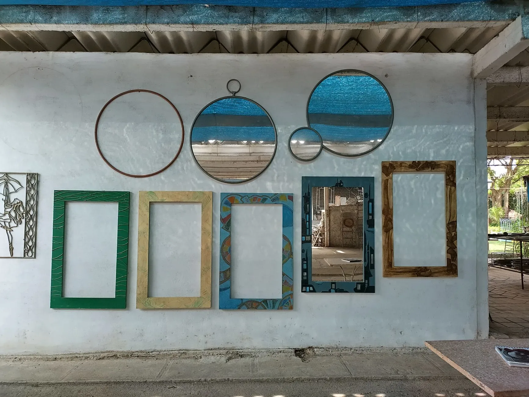 A collection of colorful frames and round mirrors displayed on a textured white wall, creating an artistic composition.