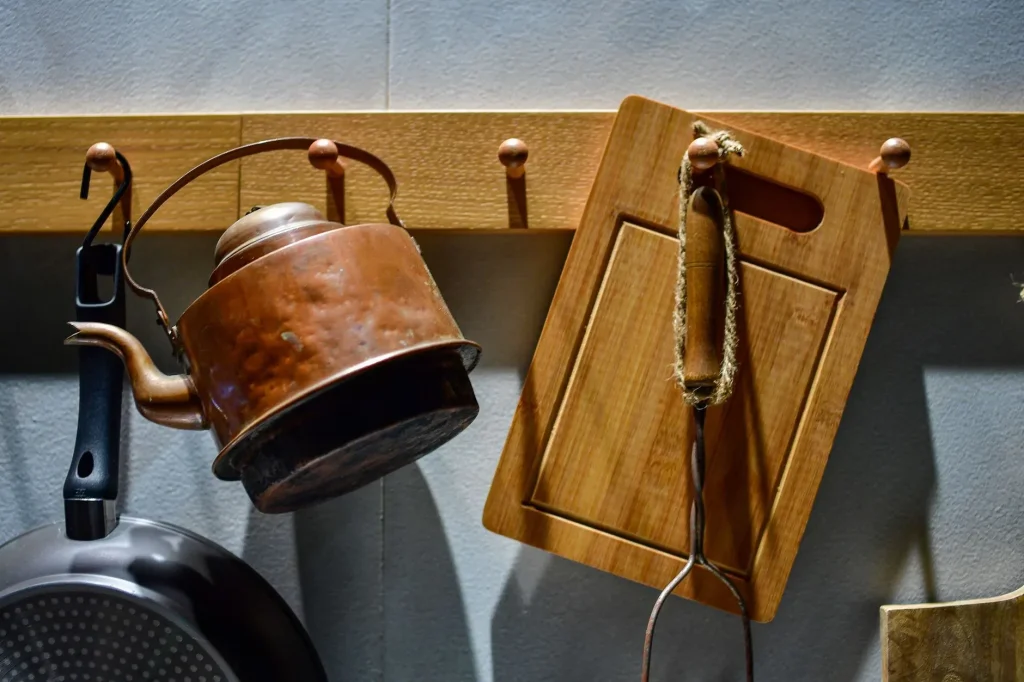 20 Cozy Kitchen Ideas That Make Cooking Feel Like the Best Part of Your Day A rustic kitchen setup featuring a copper kettle and wooden cutting board hanging against a textured wall.