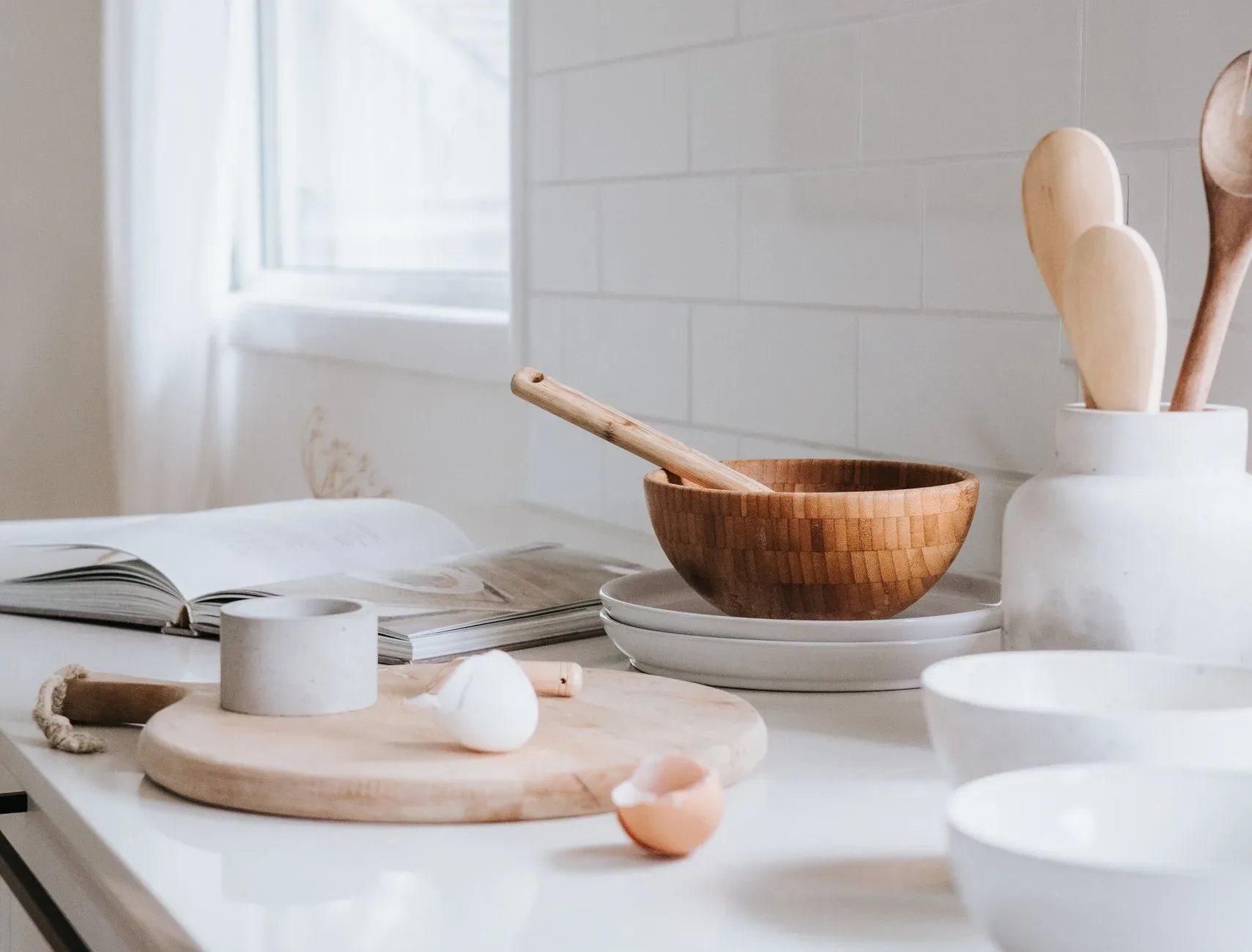 20 Cozy Kitchen Ideas That Make Cooking Feel Like the Best Part of Your Day A serene minimalist kitchen setup featuring wooden bowls, spoons, and ceramic ware on a marble surface.