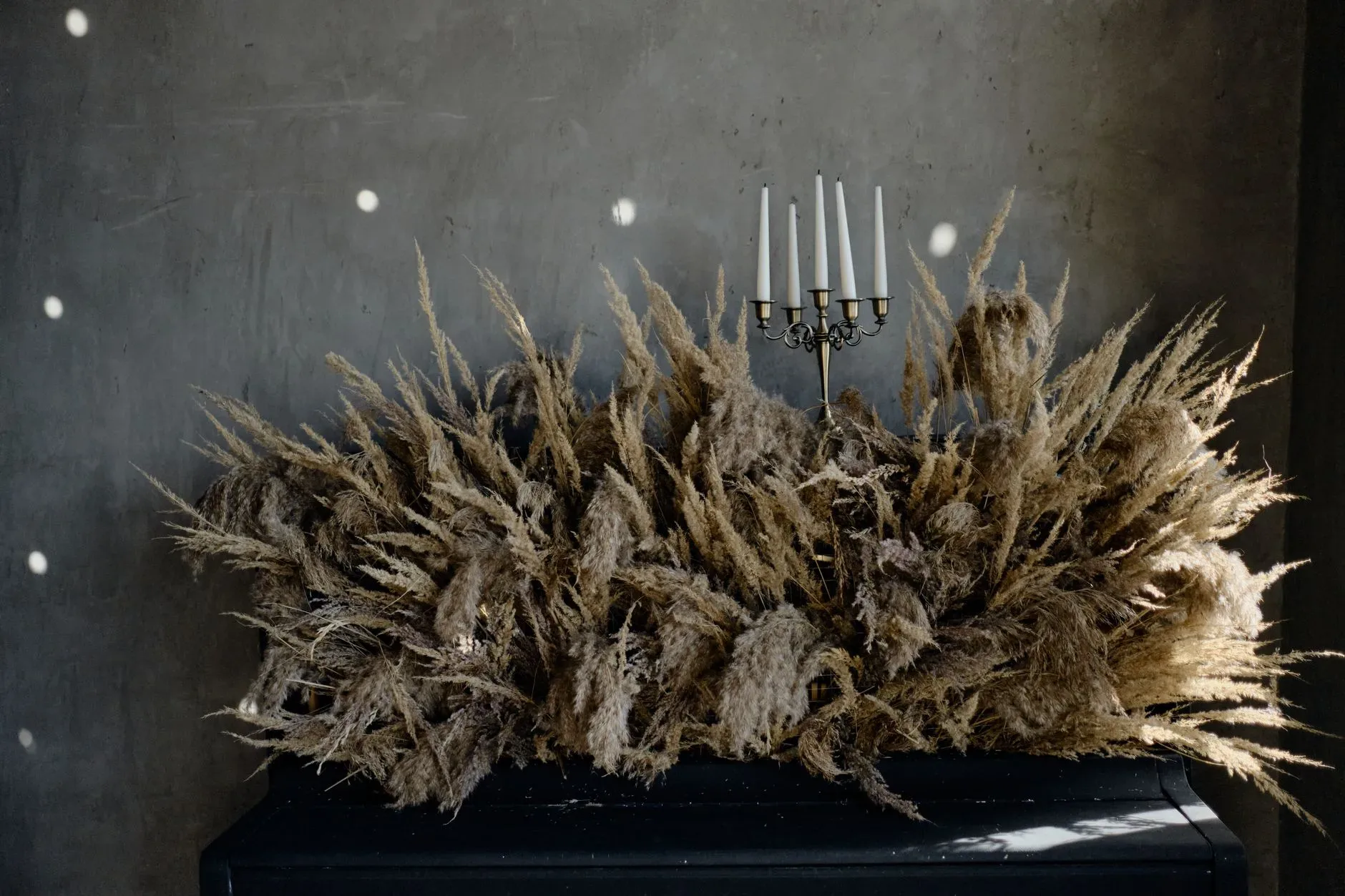 12 Wall Decor Ideas That Turn Every Blank Wall Into Something Beautiful A sophisticated setup featuring a candelabra against a backdrop of pampas grass, offering a rustic elegance.