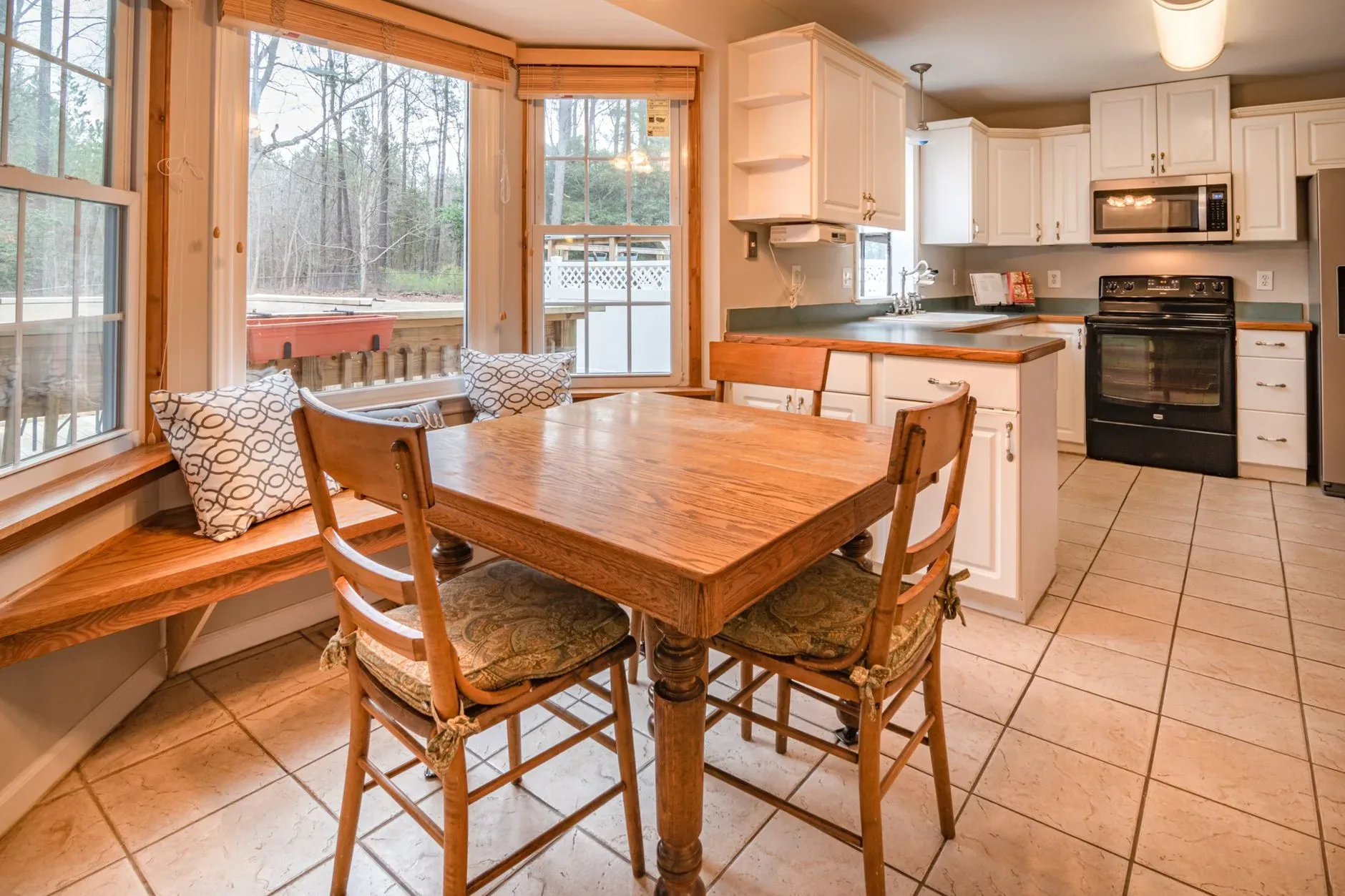 20 Cozy Kitchen Ideas That Make Cooking Feel Like the Best Part of Your Day Bright kitchen with wooden dining table, chairs, and large windows offering natural light.