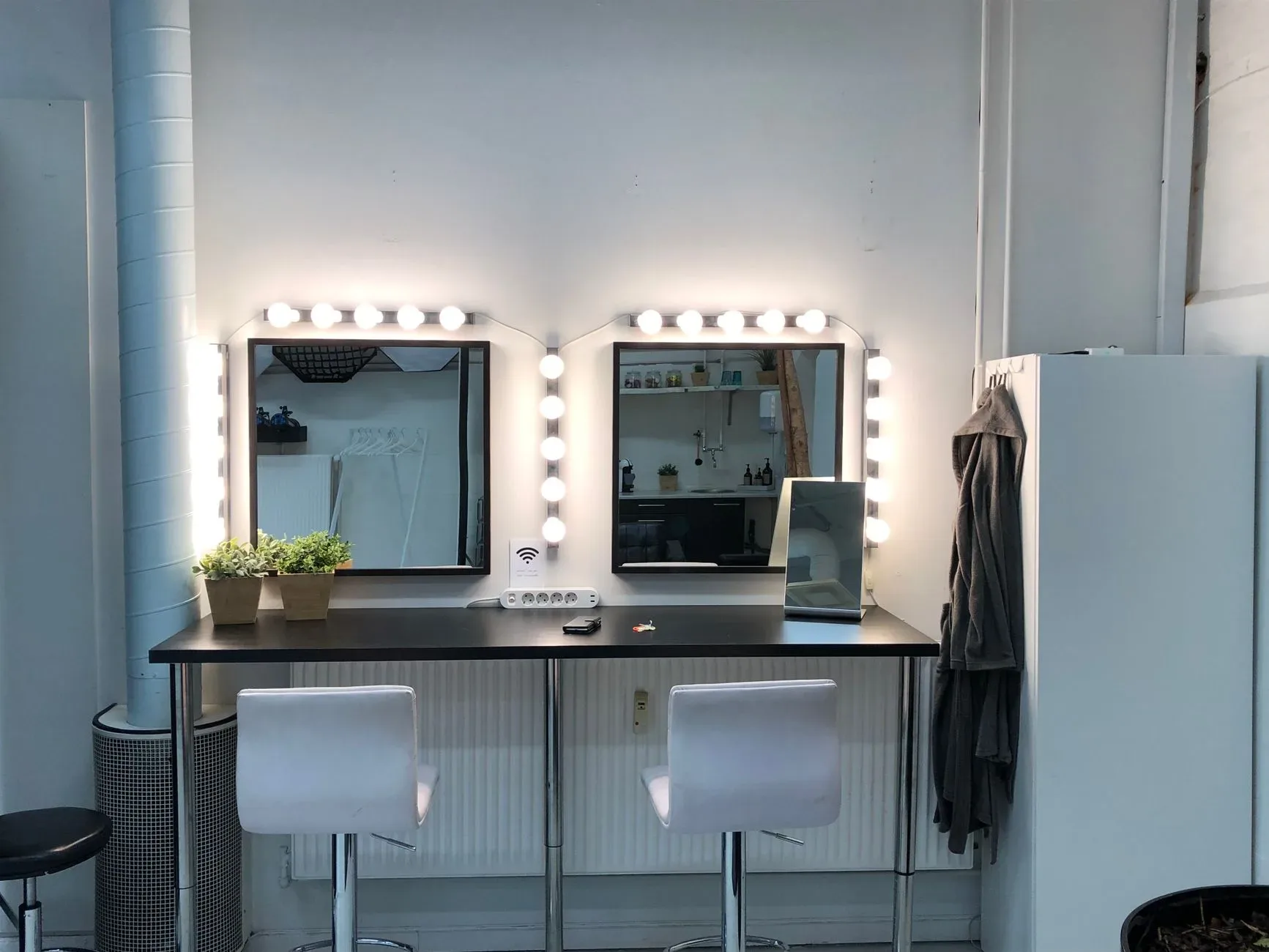 Brightly lit vanity station with mirrors and minimalist design, ideal for makeup and styling.