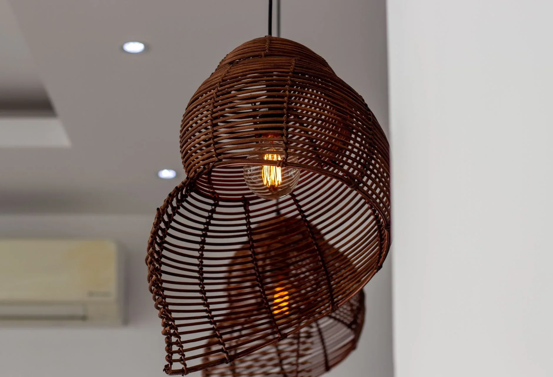 15 Wood Kitchen Ideas That Bring Warmth and Character to Any Home Close-up of a woven rattan pendant light illuminating a modern room interior.