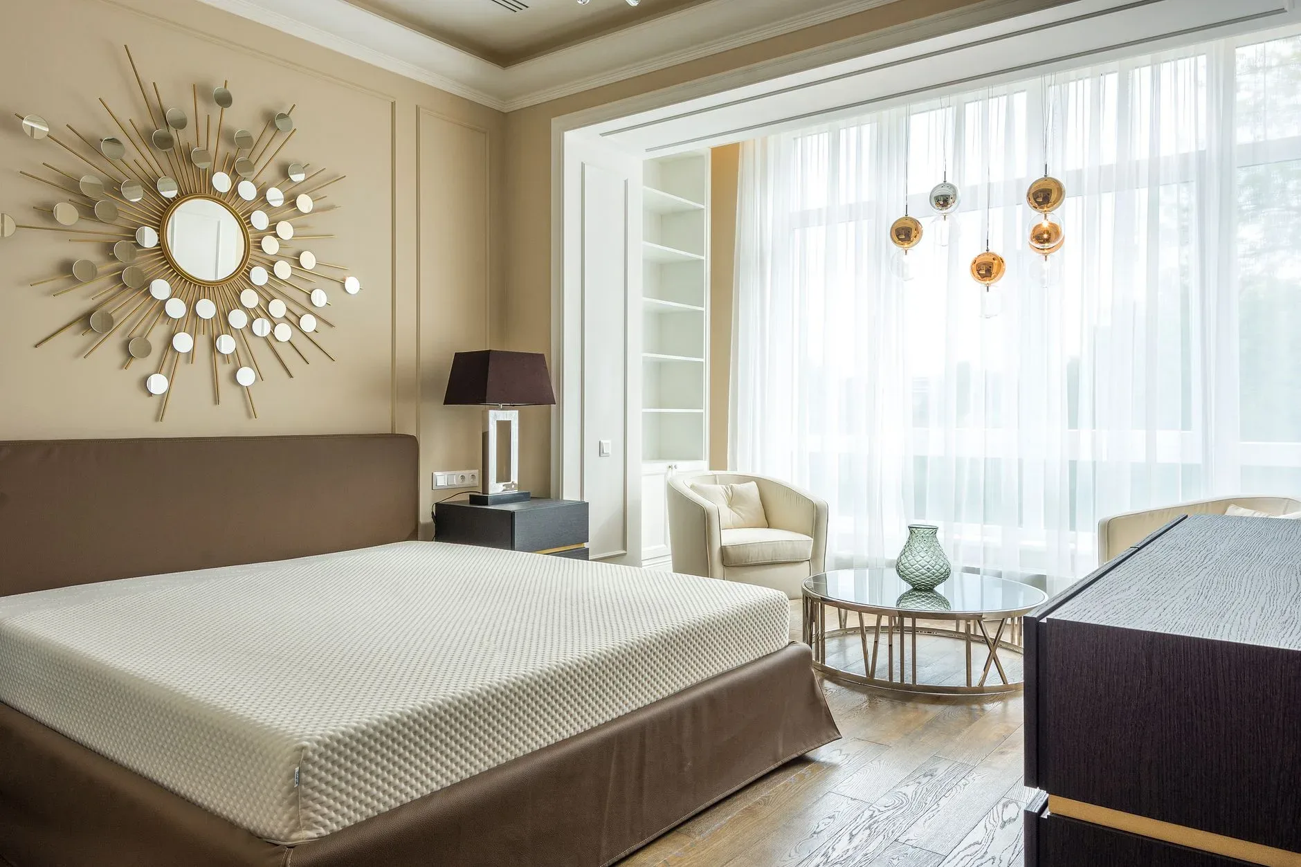 Comfortable big bed with wooden furniture and wide window with white curtain in daylight