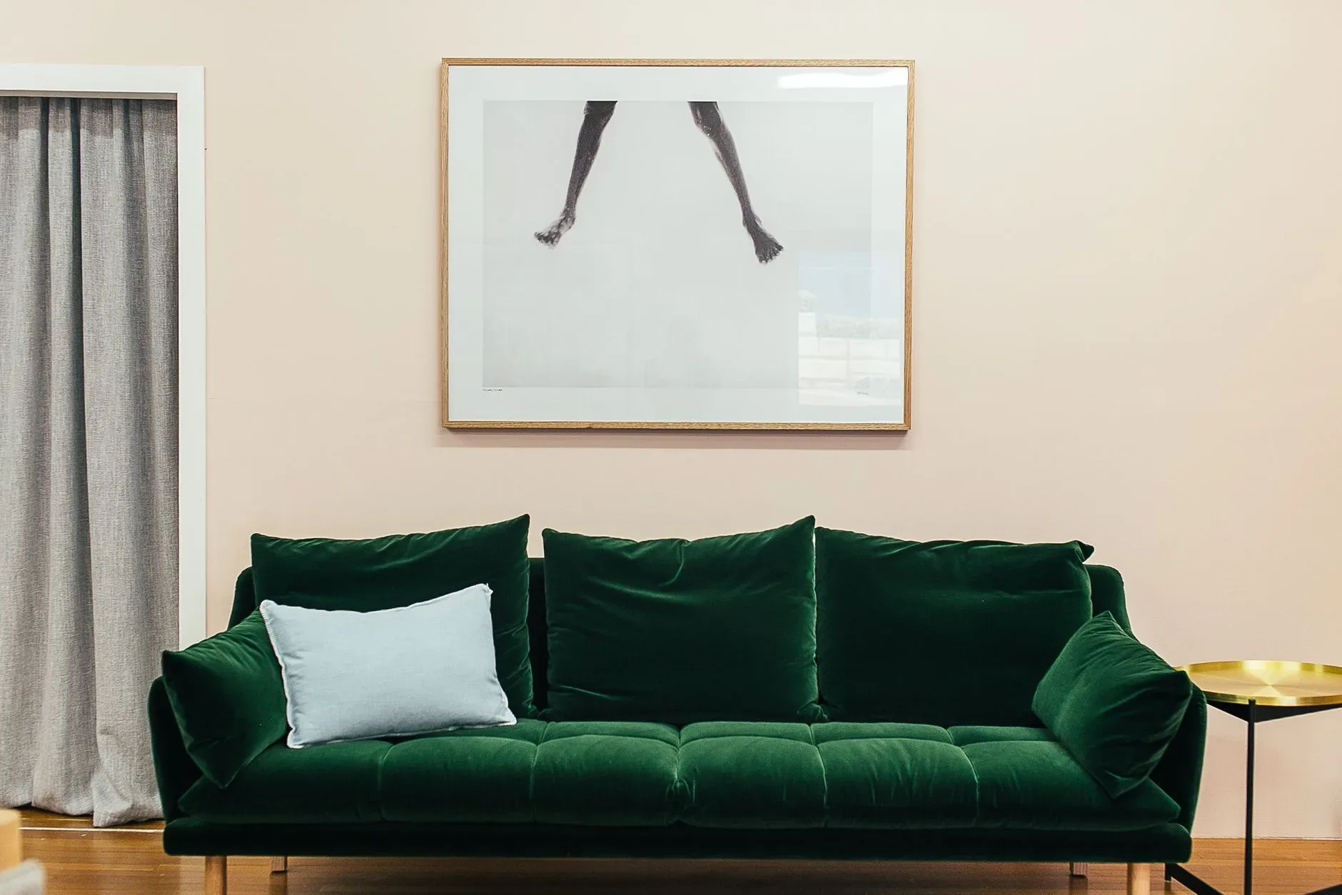15 High-End Living Room Ideas for Small Spaces Comfortable green velour sofa with soft cushions and small round table placed on parquet floor near wall with creative framed picture in stylish living room