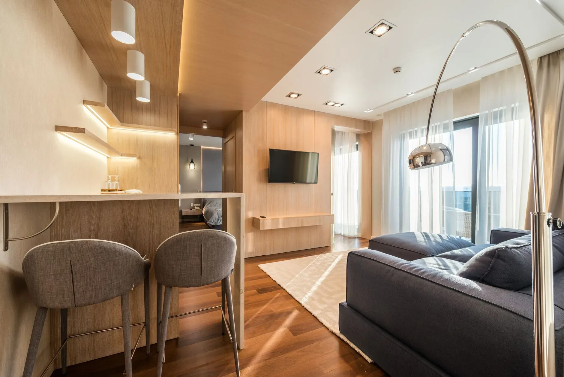 15 High-End Living Room Ideas for Small Spaces Comfortable sofa and carpet opposite TV set hanging on wall with chairs at counter in kitchen