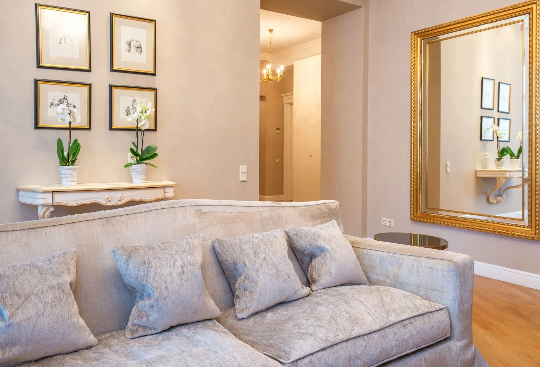 15 High-End Living Room Ideas for Small Spaces Interior of big couch with cushions placed against shelf with blooming orchids under pictures hanging on painted wall