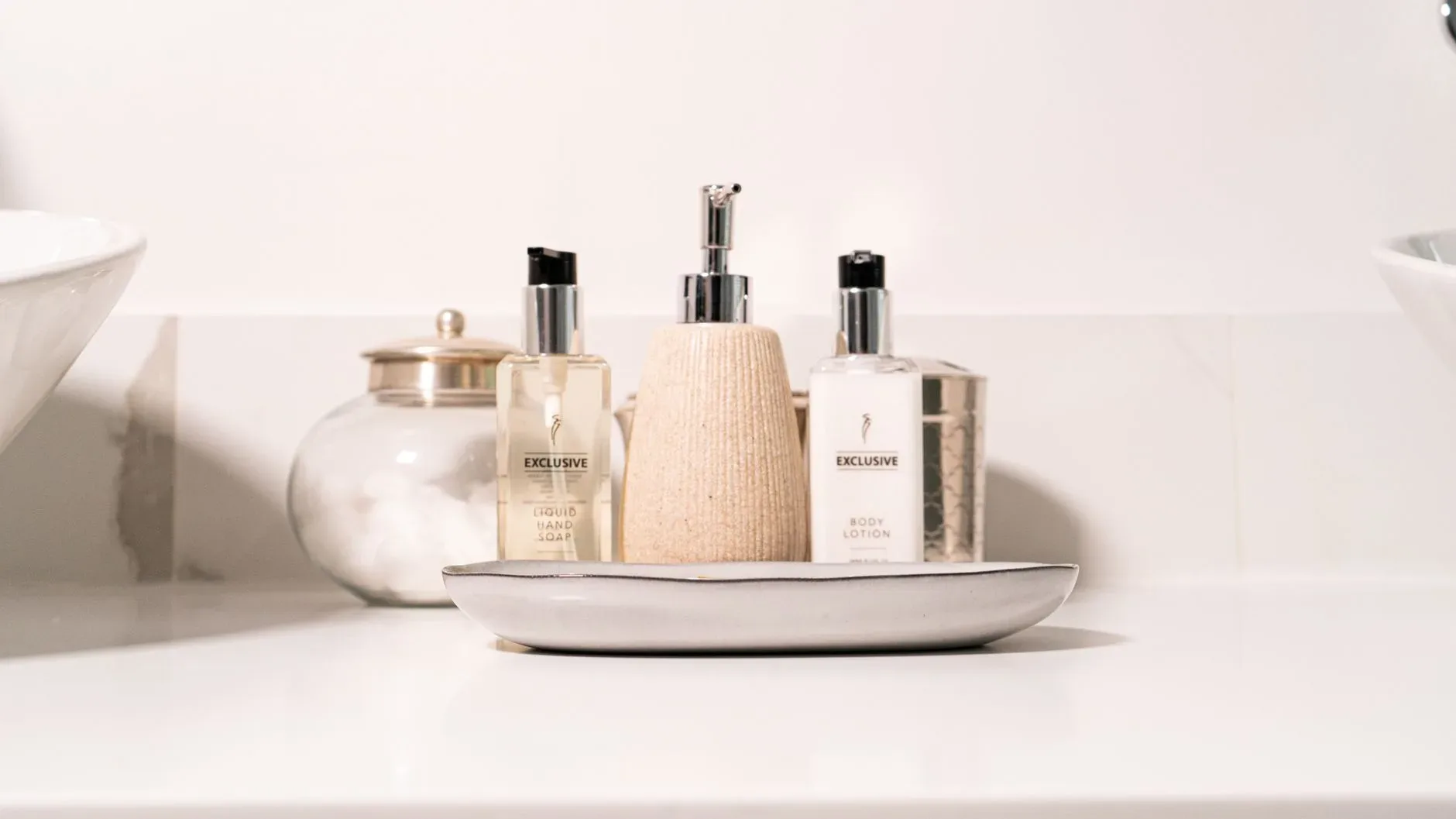 15 White Bathroom Aesthetic Ideas on a Budget Minimalist bathroom setup with hand soap and lotion in a modern setting.