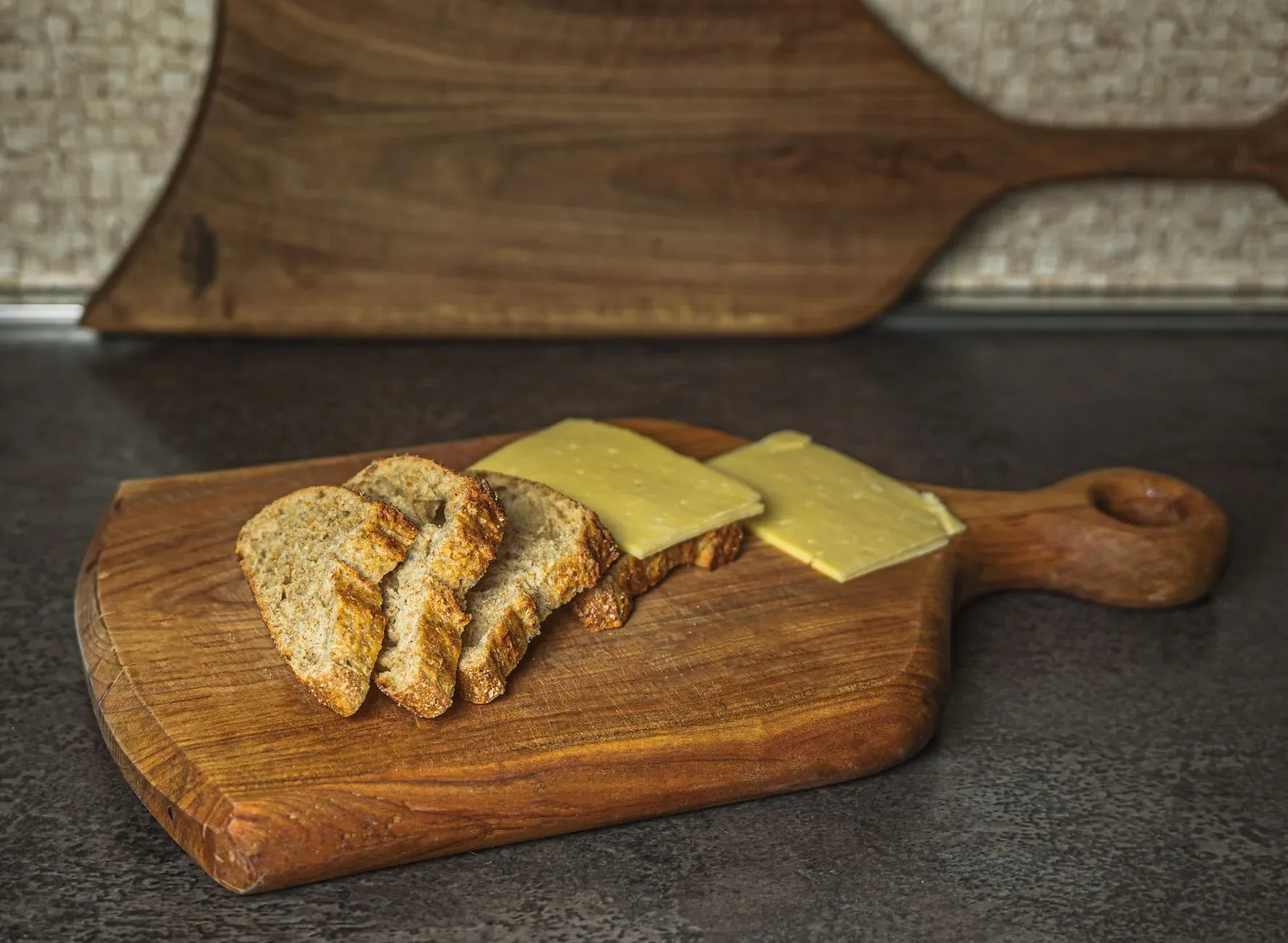 15 Wood Kitchen Ideas That Bring Warmth and Character to Any Home Sliced rustic bread paired with cheese on a wooden board, perfect for a simple culinary setting.