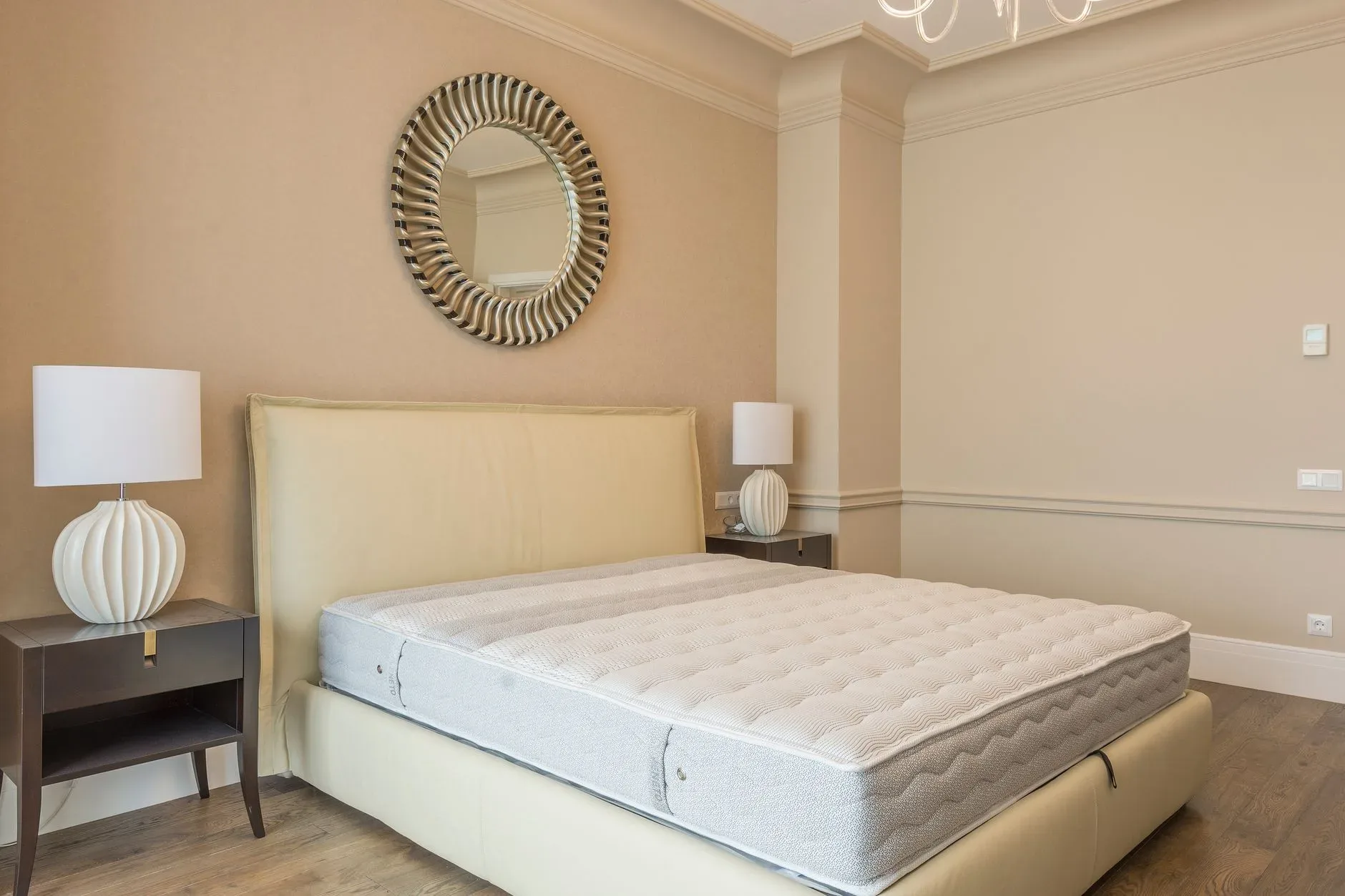 Spacious bedroom featuring modern decor, elegant lighting, and a plush bed with neutral tones.