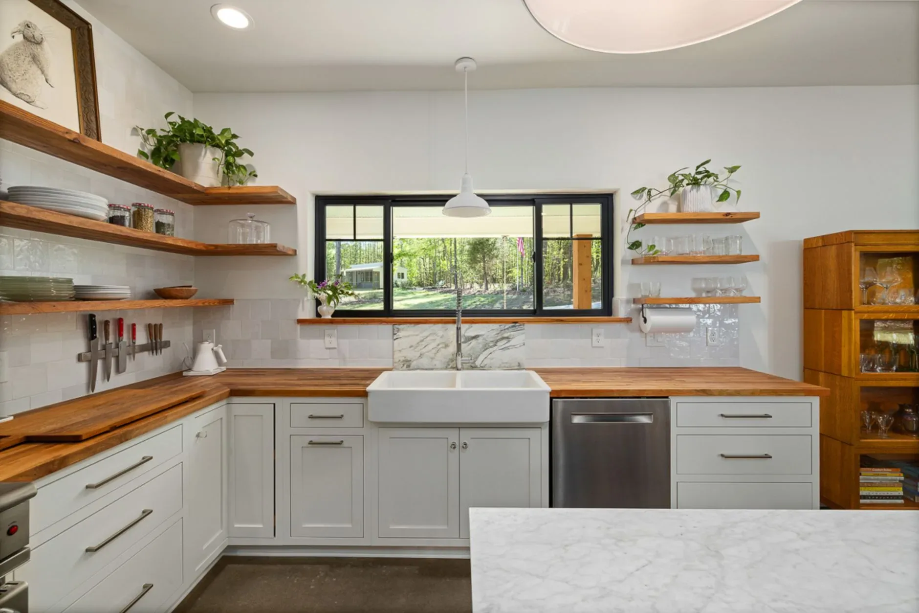 15 Wood Kitchen Ideas That Bring Warmth and Character to Any Home Stylish kitchen featuring open shelving, farmhouse sink, and wooden countertops with a view outside.