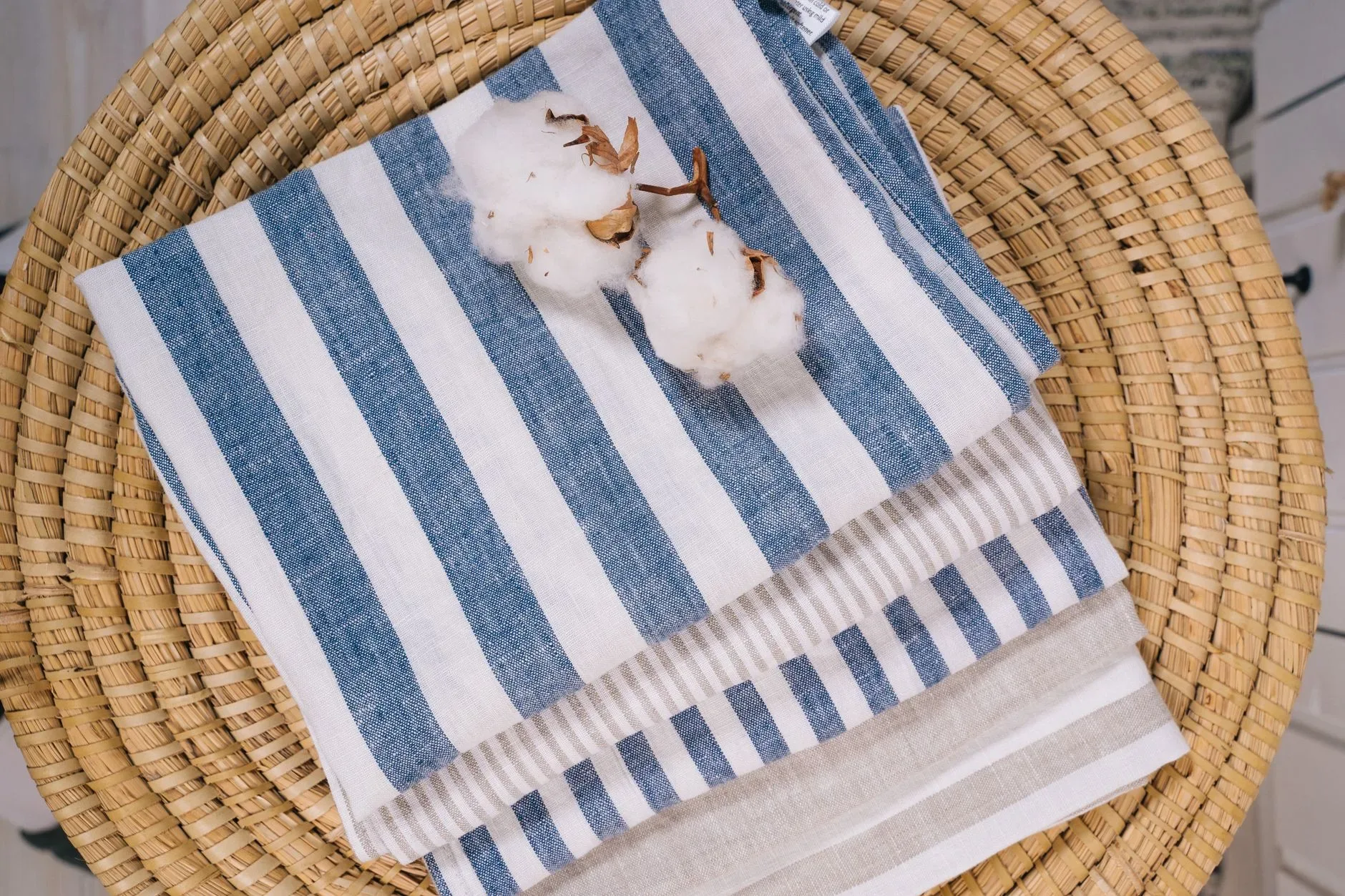18 Cozy Kitchen Decor Ideas for a Warm Home Top view of striped linen towels with cotton flowers on a rattan surface.