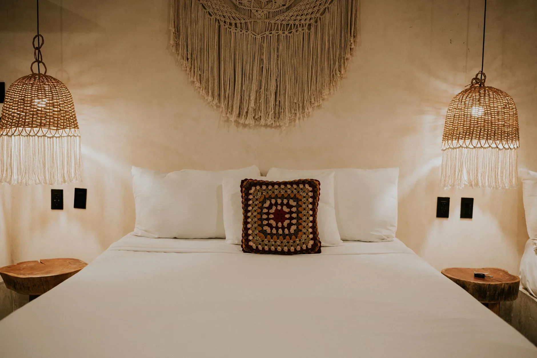 12 Wall Decor Ideas That Turn Every Blank Wall Into Something Beautiful Warm bohemian bedroom with macrame decor and wicker lampshades for a cozy ambiance.